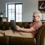 Adulto mayor aprendiendo a usar WhatsApp en su teléfono con ayuda de un familiar joven