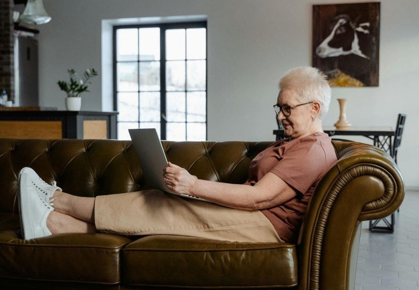 Adulto mayor aprendiendo a usar WhatsApp en su teléfono con ayuda de un familiar joven