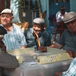 Adulto mayor sonriendo en reunión familiar en el hogar, rodeado de personas queridas