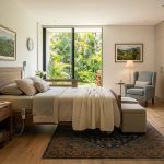 Dormitorio cálido y ordenado con luz natural matutina, tonos de madera y una atmósfera de absoluta serenidad.